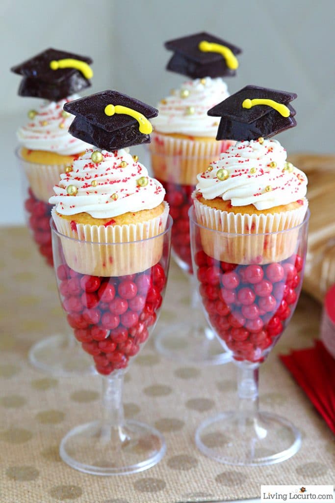 Funfetti graduation cupcakes on top of two glasses holding red candies