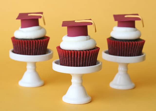3 graduation hat cupcakes on a white cupcake stands