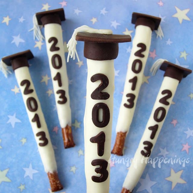 Graduation pretzel pops topped with graduation hat toppers and dates on the pretzels