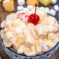 pineapple fluff in blue patterned bowl on wood surface with cherry on top.