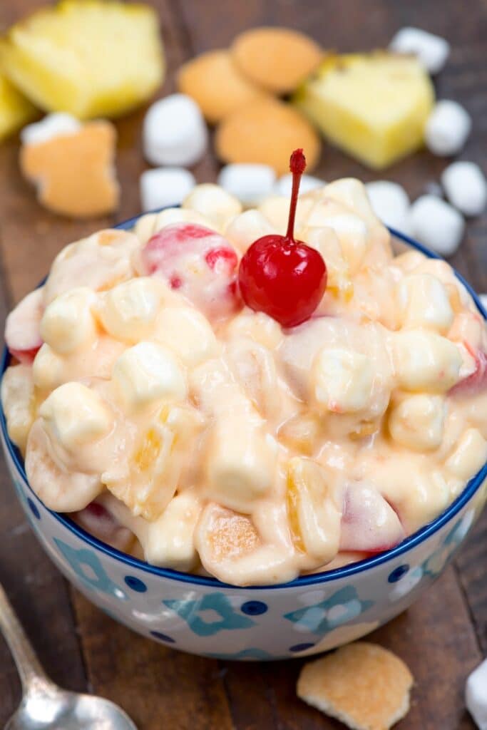 pineapple fluff in blue patterned bowl on wood surface with cherry on top.