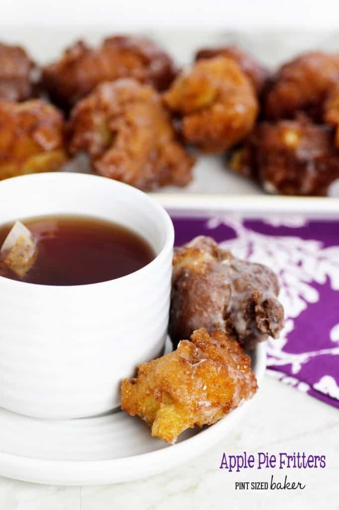 apple pie fritters on a white plate and a white cup sitting on the same plate with some sauce inside