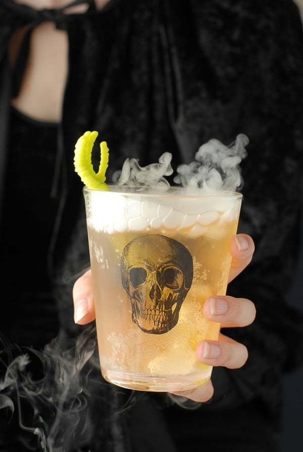 The Grave Digger cocktail in a glass with a skull on it and smoke coming out the top