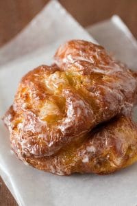 two apple fritter doughnuts on parchment paper