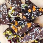 Various varieties of Chocolate bark shards on wooden chopping board