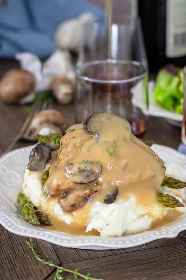Slow Cooker Chicken Thighs on a white plate with asparagus and gravy