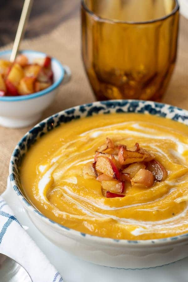 a bowl of roasted butternut squash soup with sautéed apples on top