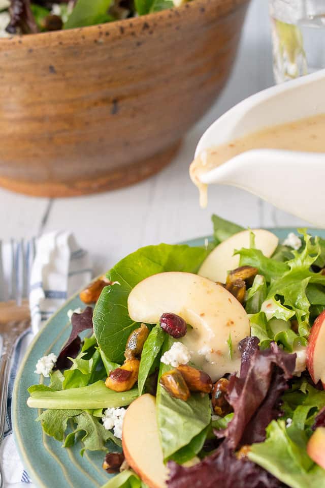 maple vinaigrette being poured onto a plate of fall salad