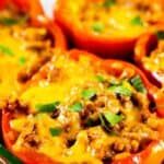 Four enchilada stuffed peppers in glass baking dish with recipe title on top