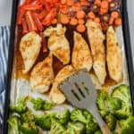 Honey garlic chicken and veggies on a sheet pan with spatula