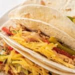 Easy chicken fajitas in tortillas on a white plate with recipe title on top