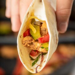 Close up shot of easy chicken fajitas in a tortilla being held in hand