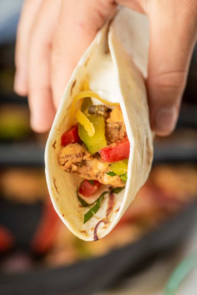 Close up shot of easy chicken fajitas in a tortilla being held in hand