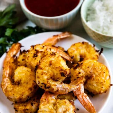 Overhead shot of air fryer coconut shrimp on a plate with dipping sauces