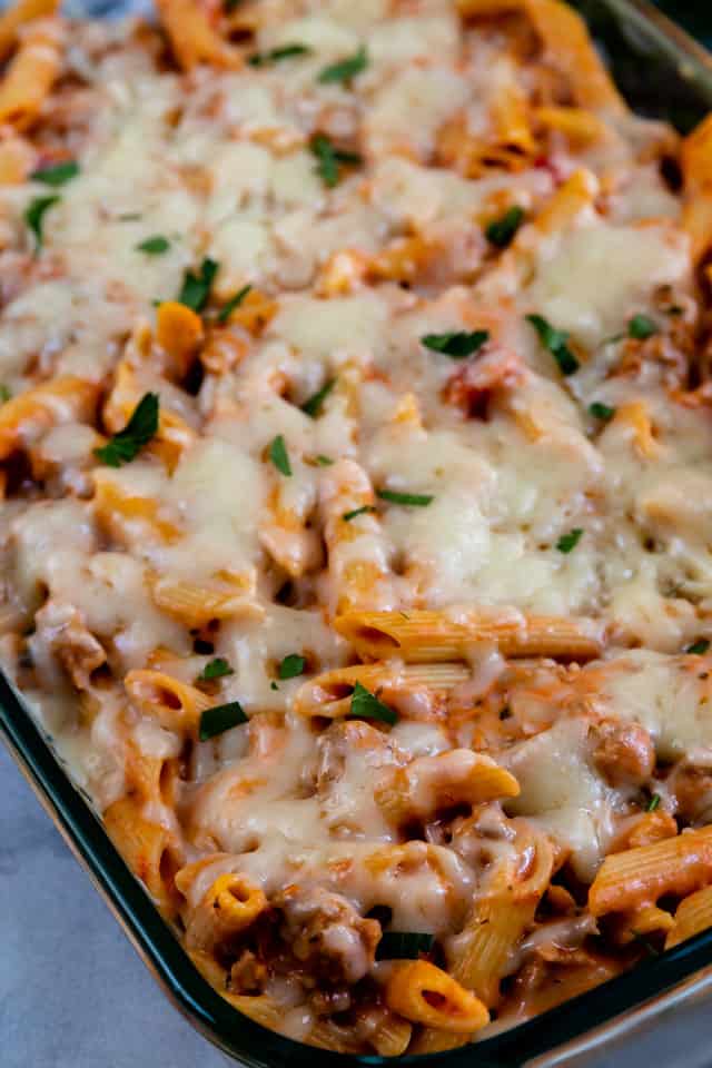 Close up shot of baked penne and sausage casserole in casserole dish