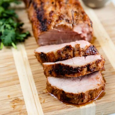 Overhead shot of pork tenderloin slices on a wood cutting board