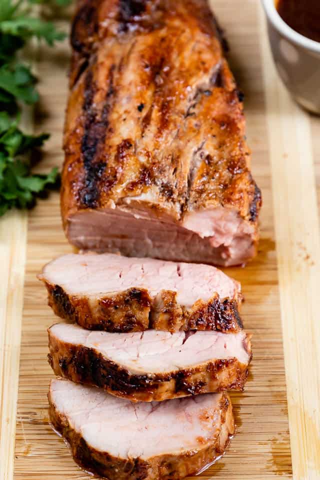 Close up of pork tenderloin slices on a wood cutting board