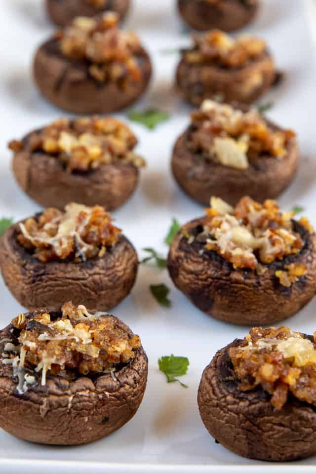Stuffed mushrooms in two rows on a white serving platter