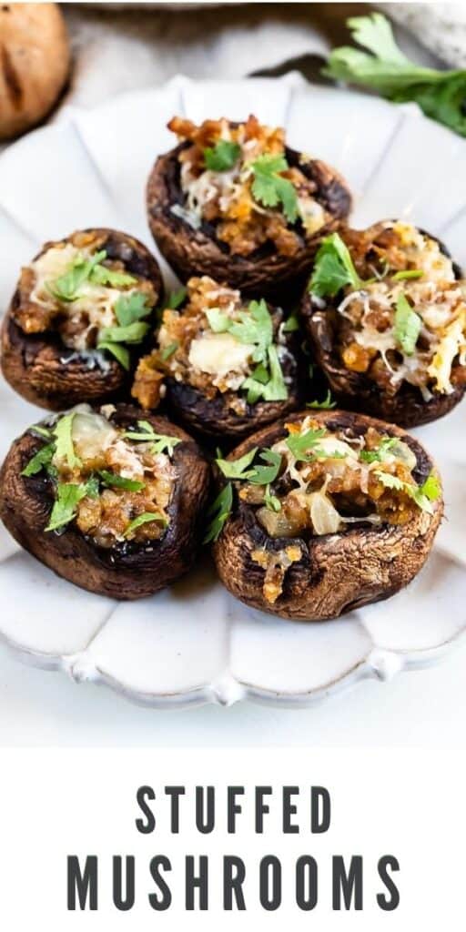 Overhead shot of 6 stuffed mushrooms on a white scallop plate with recipe title on bottom of image