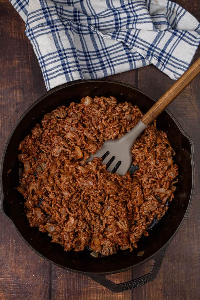 Overhead shot of ground beef in an iron skillet with spatula