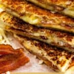 Grilled cheese sandwiches cut in half and stacked on top of eachother surrounded by cheese and bacon with recipe title on bottom of image