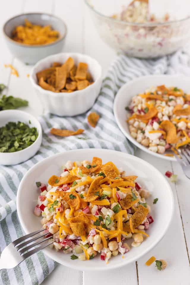Frito corn salad in bowls on table with ingredients in background