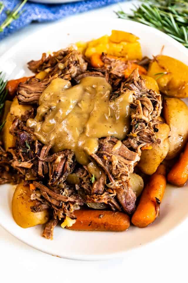 Pot roast on a white plate with brown gravy on top