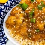 Overhead close up shot of orange chicken on a bed of rice in a white bowl with recipe title on bottom of image