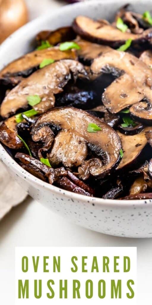 Close up photo of oven seared mushrooms in a serving bowl with recipe title on bottom of image