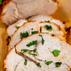 Roasted turkey breast on a wood cutting board with three pieces sliced off