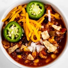 Overhead shot showing bowl of turkey chili with cheese, onions and jalapenos on top