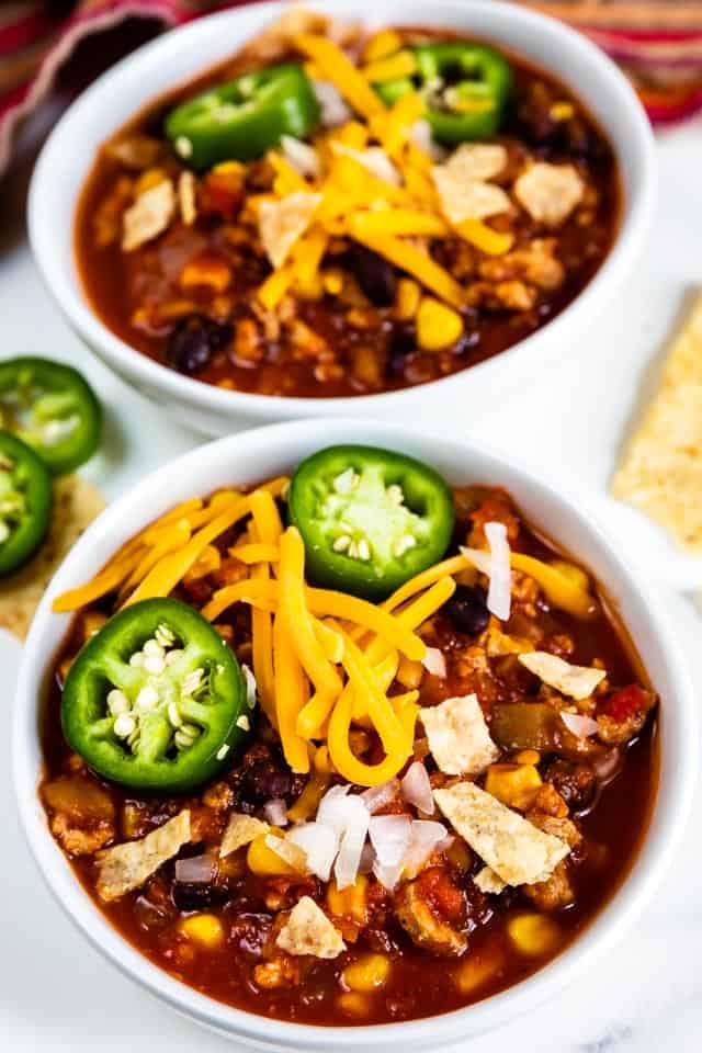 Overhead shot of two bowls filled with turkey chili and topped with cheese and jalapenos