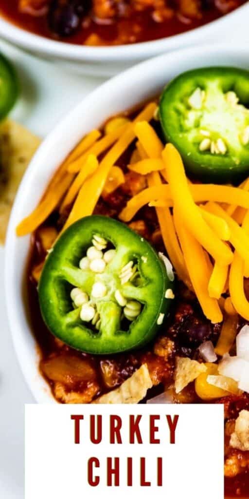 Extreme close up of turkey chili in a bowl with toppings and recipe title on bottom of image
