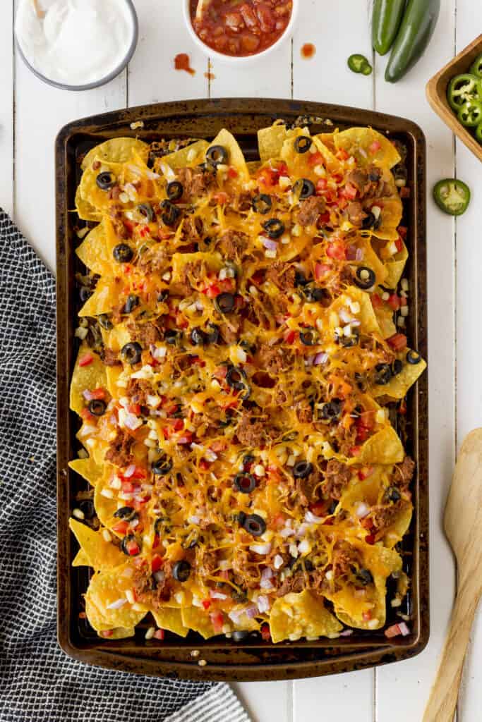 Overhead view of sheet pan nachos with all the toppings on top