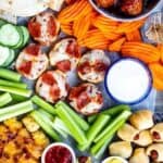 Overhead view of appetizer board filled with different appetizers and snacks with recipe title on bottom of image