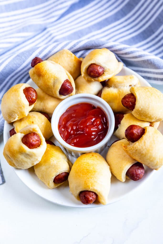 plate of pigs in a blanket with ketchup.