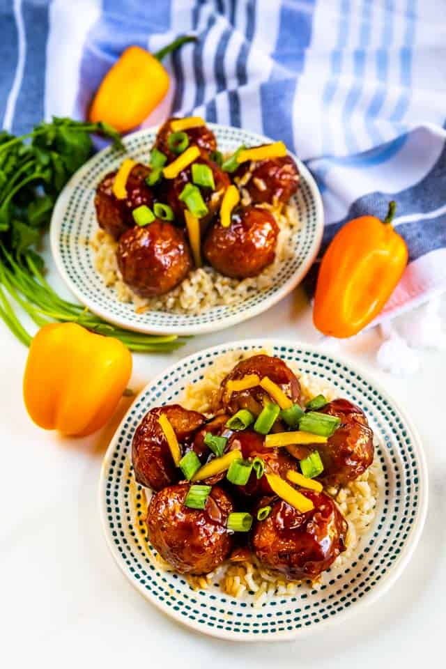 Two plates of teriyaki meatballs over white rice with bell peppers