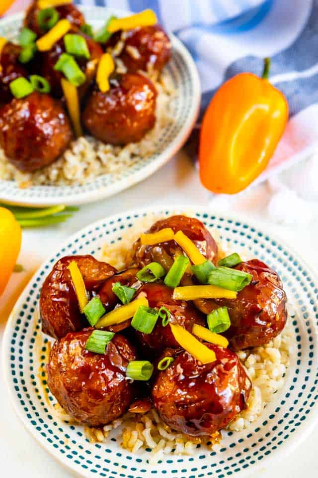 Plated teriyaki meatballs with yellow peppers and green onions on top