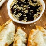Close up shot of air fryer potstickers with dipping sauce and recipe title on top of image