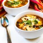 Two bowls of easy chicken tortilla soup with spoon next to bowl
