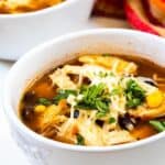 Close up of two bowls of chicken tortilla soup with recipe title on bottom of photo