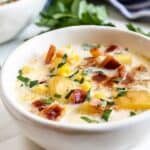 Two bowls of corn chowder topped with herbs and recipe title on bottom of photo