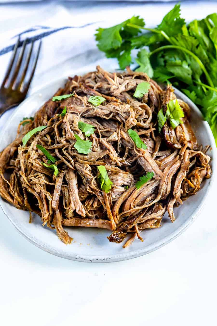 Overhead shot of shredded flank steak with herbs on top