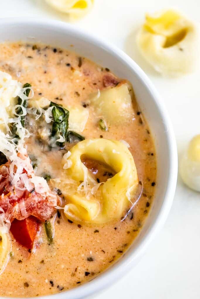 Close up overhead shot of crockpot tortellini soup in a white bowl