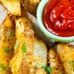 Overhead shot of potato wedges with ketchup and recipe title on bottom of photo