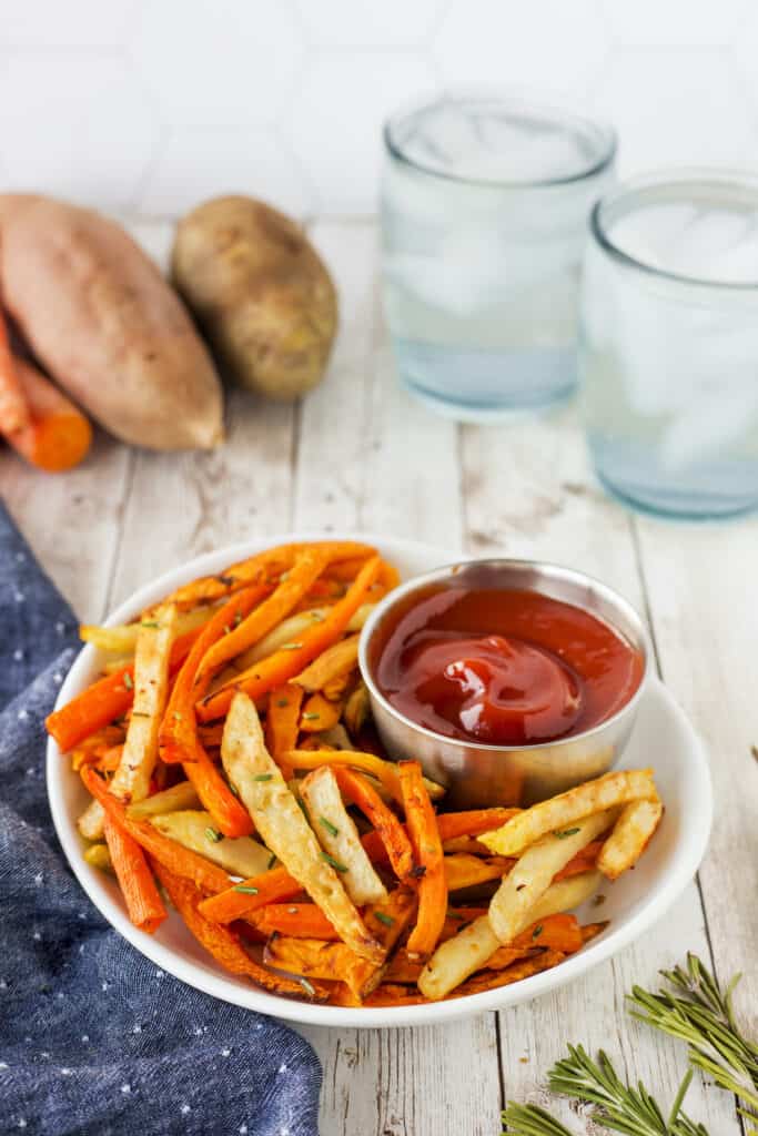 Air fryer trio rosemary fries in a white dish with ketchup and ingredients in the background