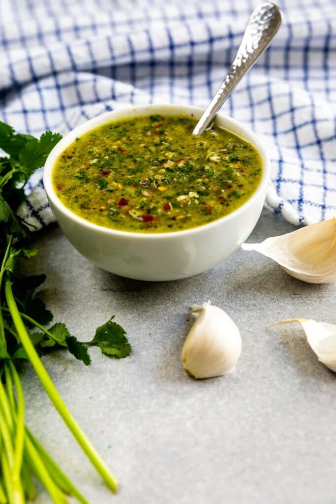 Bowl of chimichurri sauce with ingredients around it