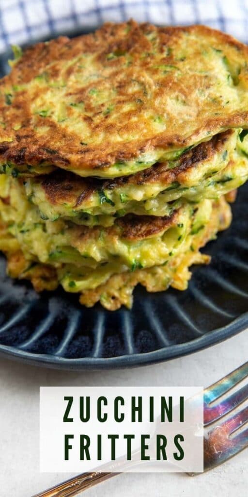 Stack of zucchini fritters on a blue plate with a fork next to it and recipe title on bottom of photo