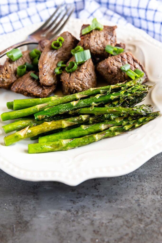 Air fryer asparagus plated next to steak