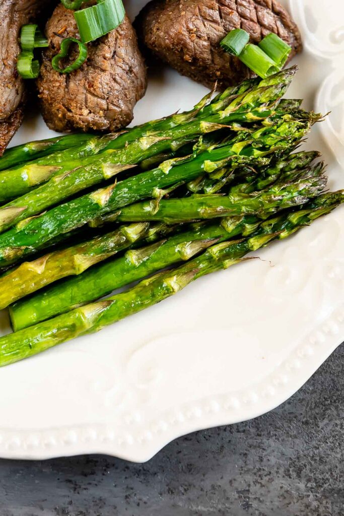 Air fryer asparagus plated next to steak